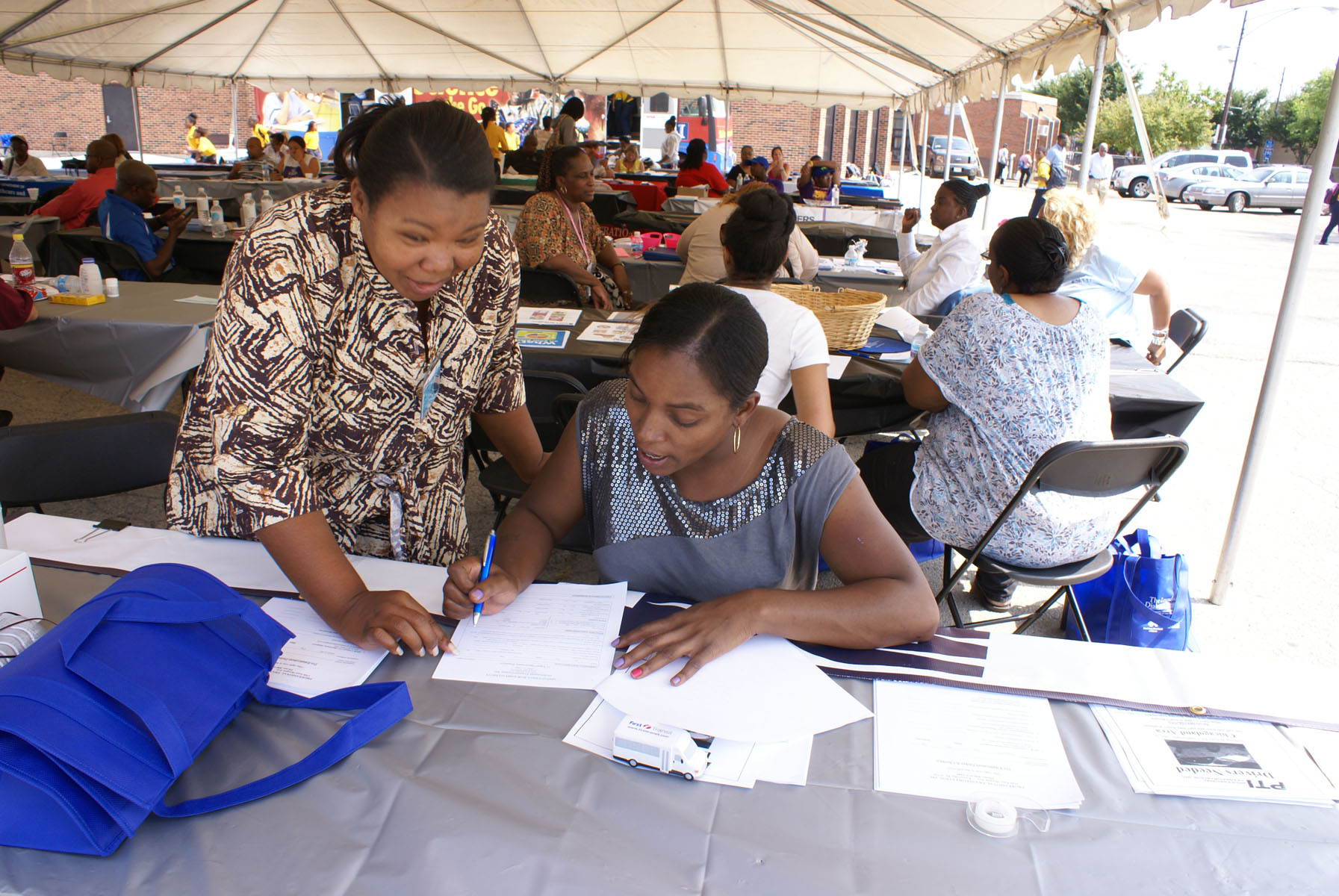 CAP staff helping a resident complete paperwork at a neighborhood resource event